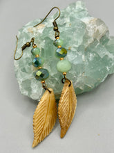 Load image into Gallery viewer, Single-stranded earring features bone carved leaf charm earrings with light mint faceted round glass beads.  Glass beads have a tint of dark green and gold shimmer. Antique antique brass plated steel ear-wire French Hook Earrings.   Measurements: 3” in length