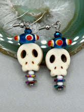 Load image into Gallery viewer, Spooky but festive skull beads with hematite bead spines and come with fiesta shaped crown glass earrings. These stylish skull earrings are perfect for adding a unique flair to any outfit. Whether you're looking for a Dia De Los Muertos accessory or simply looking to draw inspiration, these goth pieces perfectly capture the vampire goth, witchy, dark, Chingona Cabrona, Latina Chicana styles. Measurements: 1 1/2” in length