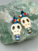 Load image into Gallery viewer, Spooky but festive skull beads with hematite bead spines and come with fiesta shaped crown glass earrings. These stylish skull earrings are perfect for adding a unique flair to any outfit. Whether you're looking for a Dia De Los Muertos accessory or simply looking to draw inspiration, these goth pieces perfectly capture the vampire goth, witchy, dark, Chingona Cabrona, Latina Chicana styles. Measurements: 1 1/2” in length