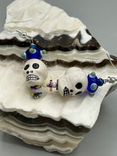 Load image into Gallery viewer, Spooky but festive Peruvian ceramic skull beads with hematite beaded spines and come with fiesta shaped crown glass earrings. These stylish skull earrings are perfect for adding a unique flair to any outfit. Whether you're looking for a Dia De Los Muertos accessory or simply looking to draw inspiration, these goth pieces perfectly capture the vampire goth, witchy, dark, Chingona Cabrona, Latina Chicana styles. Measurements: 1 1/4” in length