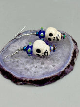Load image into Gallery viewer, Spooky but festive Peruvian ceramic skull beads with hematite beaded spines and come with fiesta shaped crown glass earrings. These stylish skull earrings are perfect for adding a unique flair to any outfit. Whether you're looking for a Dia De Los Muertos accessory or simply looking to draw inspiration, these goth pieces perfectly capture the vampire goth, witchy, dark, Chingona Cabrona, Latina Chicana styles. Measurements: 1 1/4” in length