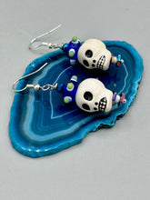 Load image into Gallery viewer, Spooky but festive Peruvian ceramic skull beads with hematite beaded spines and come with fiesta shaped crown glass earrings. These stylish skull earrings are perfect for adding a unique flair to any outfit. Whether you're looking for a Dia De Los Muertos accessory or simply looking to draw inspiration, these goth pieces perfectly capture the vampire goth, witchy, dark, Chingona Cabrona, Latina Chicana styles. Measurements: 1 1/4” in length