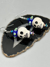 Load image into Gallery viewer, Spooky but festive Peruvian ceramic skull beads with hematite beaded spines and come with fiesta shaped crown glass earrings. These stylish skull earrings are perfect for adding a unique flair to any outfit. Whether you're looking for a Dia De Los Muertos accessory or simply looking to draw inspiration, these goth pieces perfectly capture the vampire goth, witchy, dark, Chingona Cabrona, Latina Chicana styles. Measurements: 1 1/4” in length