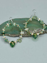 Load image into Gallery viewer, Natural aventurine stone chips, turquoise, and gold glass beads are strung together to form these stylish hoop earrings. The dark green pressed glass leaf charm complements the design, creating an iridescent, shimmery finish with subtle hues of gold, purple, blue, and pink.  Measurements: 2" length