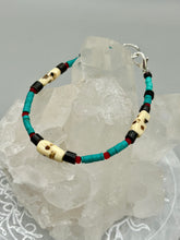 Load image into Gallery viewer, These stylish skull bracelet is perfect for adding a unique flair to any outfit. Whether you're looking for a Dia De Los Muertos accessory or simply looking to draw inspiration, these goth pieces perfectly capture the vampire goth, witchy, dark, Chingona Cabrona, Latina Chicana styles. Skull-shaped bone beads adorned with dark brown, turquoise, and gold beads make up this unique statement piece. Measurements: Bracelet: 7 1/2"