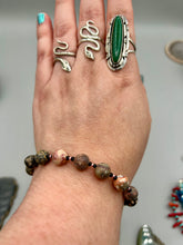 Load image into Gallery viewer, Nature inspired single-strand leopard jasper round stone beads with gold and black glass beaded bracelet. Leopard jasper stone has an array on neutral earth tones including soft pink, salmon, and gray tones. Crafted with metal wire and fastened with a lobster claw clasp. Measurements: Bracelet: 7 1/2" in length