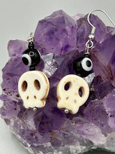 Load image into Gallery viewer, Spooky but festive skull beads with black and white evil eye bead earrings. These stylish skull earrings are perfect for adding a unique flair to any outfit. Whether you're looking for a Dia De Los Muertos accessory or simply looking to draw inspiration, these goth pieces perfectly capture the vampire goth, witchy, dark, Chingona Cabrona, Latina Chicana styles. Measurements: 1” in length
