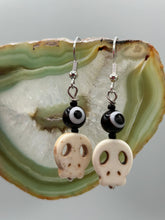 Load image into Gallery viewer, Spooky but festive skull beads with black and white evil eye bead earrings. These stylish skull earrings are perfect for adding a unique flair to any outfit. Whether you're looking for a Dia De Los Muertos accessory or simply looking to draw inspiration, these goth pieces perfectly capture the vampire goth, witchy, dark, Chingona Cabrona, Latina Chicana styles. Measurements: 1” in length