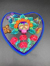 Load image into Gallery viewer, Frida Kahlo inspired calavera with a dark wood frame, this Day of the Dead wall decor piece is perfect for adding a traditional Mexican folk art touch to any home. Featuring an intricately detailed clay calavera in the style of Frida Kahlo, this Day of the Dead wall art decor is sure to be the centerpiece of any home décor. The calavera is wearing Frida's iconic crown of flowers and with several butterflies around her, ensuring it will bring both a unique and inspiring look to any wall.