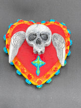 Load image into Gallery viewer, This Memento Mori Wall Art Decor is a unique statement piece to add a pop of color to your walls. Handcrafted with black and white polymer clay, acrylic paint, and a wood frame, the skull artwork is decorated with small turquoise and yellow-orange flowers and a turquoise and gold cross. Perfect for a Day of the Dead altar or a witchy home decor display.