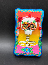 Load image into Gallery viewer, Transform your walls with this handcrafted polymer clay wall art. Showcasing a vibrant Frida Kahlo inspired calavera with hand-beaded floral crown, this Day of the Dead wall decor piece is perfect for adding a traditional Mexican folk art touch to any home.
