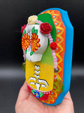 Load image into Gallery viewer, Transform your walls with this handcrafted polymer clay wall art. Showcasing a vibrant Frida Kahlo inspired calavera with hand-beaded floral crown, this Day of the Dead wall decor piece is perfect for adding a traditional Mexican folk art touch to any home.