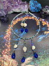 Load image into Gallery viewer, This adjustable collar-style necklace features two shimmery strands of silver and blue glass beads, with three skull charms boasting large, luminous blue teardrop glass beads adding extra shimmer and movement. Measurements: Necklace is 14 3/8” adjustable up to 18" in length