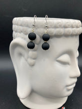 Load image into Gallery viewer, These flat matte black glass bead earrings are perfect for creating a cocktail chic ensemble. With a round shape and silver plated floral bead, this timeless piece is ideal for special occasions such as weddings. Its minimalist look exudes effortless elegance. Measurements: 1 1/4” in length