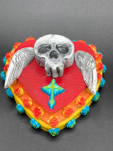 Load image into Gallery viewer, This Memento Mori Wall Art Decor is a unique statement piece to add a pop of color to your walls. Handcrafted with black and white polymer clay, acrylic paint, and a wood frame, the skull artwork is decorated with small turquoise and yellow-orange flowers and a turquoise and gold cross. Perfect for a Day of the Dead altar or a witchy home decor display.