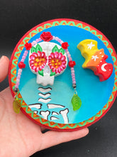 Load image into Gallery viewer, Transform your walls with this handcrafted polymer clay wall art. Showcasing a vibrant Frida Kahlo inspired calavera with hand-beaded floral crown, this Day of the Dead wall decor piece is perfect for adding a traditional Mexican folk art touch to any home.
