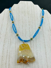 Load image into Gallery viewer, This two-strand necklace features an array of glass beads, including shades of green, blue and turquoise, as well as gold and green. Topped off with a show-stopping yellow agate stone in turquoise, the necklace boasts an eye-catching color combination. Measurements: Necklace is 15 1/2", adjustable up to 17”