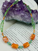 Load image into Gallery viewer, This unique, double-strand necklace consists of a blend of glass beads, including multi-green and rectangular, faceted orange glass beads, and is accented with gold and light blue elements. The vibrant combination is perfect for any summer look and will enhance any outfit.  Measurements:  Necklace is 16” and can be adjusted up to 18"