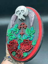 Load image into Gallery viewer, This Memento Mori Wall Art Decor is a one-of-a-kind art piece, skillfully crafted with a black polymer clay skull and wings on a dark red wood frame, decoratively woven with dark red roses and vines. It's perfect for adding an eye-catching touch to any wall and makes a unique, bold gift.  Measurements: H 7" x W 5” x D 1 1/2"