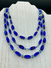 Load image into Gallery viewer, This vibrant royal blue and silver-tone necklace is adjustable and features an eye-catching three-strand design. The rectangular blue glass beads are predominant, complemented by a blend of lighter blue and silver beads for an intriguing multi-hued finish. By mixing shapes and tones, it creates a complex, dimensional look. The draped effect adds a fierce yet elegant pizzazz to any outfit. Perfect for the season of Spring, it will bring a splash of rich color to your wardrobe.