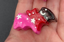Load image into Gallery viewer, Cute and spooky magnet design to adorn your refrigerator, lockers, workstation, toolbox, or dishwasher. This hand-sculpted clay bat statuette boasts stunning ombre coloration, transitioning from black to dark red to pink to recreate the breathtaking look of a starry night sky. H 1” x W 2” x D 1/2”