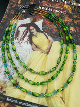 Load image into Gallery viewer, This adjustable glass beaded necklace features a combination of vivid green, blue, and gold hues and a mixture of shapes, creating an eye-catching spectrum of colors and a complex look. The rectangular green glass beads form the predominant part of the three-strand piece, which offers a bold and elegant fashion statement that is ideal for the Spring season. Measurements: Necklace is 17” in length, can be adjusted up to 19" in length