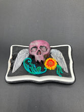 Load image into Gallery viewer, This unique wall art decor, crafted with hand-molded polymere clay and painted on a wooden frame, brings to life a classic Dia De Los Muertos Calavera with its fiery-red skull and bright yellow-orange flower and vine accents. Perfect for accenting your crystal display, witchy altar, or indoor garden.