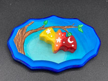 Load image into Gallery viewer, Starry Night Mini Bat Wall Art Decor. A perfect hanging art piece to add a pop of color to your wall, next to your display of crystals or witchy altar. Bat figurine is made of polymer clay, painted ombre colors from light yellow, to orange, then to dark red with white stars and crescent moon flying over the sun rise sky. Dark blue wood frame matches the light blue sky. Art come ready to hang with a sawtooth hangers on back. Measurements: H 3" x W 5” x D 1 1/2"