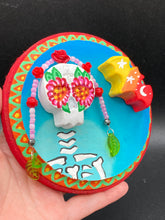 Load image into Gallery viewer, Transform your walls with this handcrafted polymer clay wall art. Showcasing a vibrant Frida Kahlo inspired calavera with hand-beaded floral crown, this Day of the Dead wall decor piece is perfect for adding a traditional Mexican folk art touch to any home.