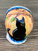 Load image into Gallery viewer, Inspired by nature, ceramic skull is full of vibrant colors and intricate details. The primary color is white with a black cat silhouette and multi-color floral motifs, along with hearts and leaves and lively colorful accents around the entire skull. Mini skull represented the eternal love for a special kitty cat in your life. Black cat silhouette is sitting on a tree branch admiring the starry night sky. Art created for all the cat lovers who adore their sweet kitty. Measurements: H 2 3/4” x W 2” x D 2”