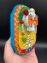 Load image into Gallery viewer, Transform your walls with this handcrafted polymer clay wall art. Showcasing a vibrant Frida Kahlo inspired calavera with hand-beaded floral crown, this Day of the Dead wall decor piece is perfect for adding a traditional Mexican folk art touch to any home.