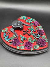Load image into Gallery viewer, This Memento Mori Wall Art Decor is a one-of-a-kind art piece, skillfully crafted with a black polymer clay skull and wings on a dark red wood frame, decoratively woven with dark red roses and vines. It's perfect for adding an eye-catching touch to any wall and makes a unique, bold gift. Measurements: H 6 3/4" x W 7” x D 1 1/2"