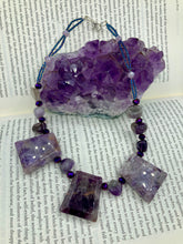 Load image into Gallery viewer, This necklace features large trapezoid-shaped Amethyst pendants and small Amethyst nuggets strung together with shimmery multicolored glass beads, creating a unique and eye-catching statement piece. Measurements: Necklace is is 15 1/2” adjustable up to 17"