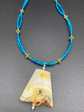 Load image into Gallery viewer, This two-strand necklace features an array of glass beads, including shades of green, blue and turquoise, as well as gold and green. Topped off with a show-stopping yellow agate stone in turquoise, the necklace boasts an eye-catching color combination. Measurements: Necklace is 15 1/2", adjustable up to 17”
