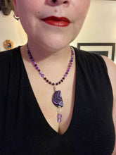 Load image into Gallery viewer, This double-stranded necklace is adorned with a large agate stone displaying a spectrum of purple shades, from light sheer to deep dark tones. The combination of purple agate and multi-colored glass beads makes this pendant a stunning addition to any summer look. Measurements: Necklace is 17” in length