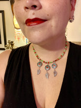 Load image into Gallery viewer, This adjustable necklace features an eye-catching Southwest-inspired design. Multi-hued glass beads, including bright green and vibrant red, are accompanied by dark red and green pendants with silver-plated feather charms. Ideal for chingona guerrera carbonas, la India princesses, warrior cosplay, and native-inspired looks. Measurements: Necklace is 15” adjustable up to 17" in length