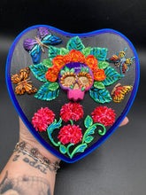 Load image into Gallery viewer, Frida Kahlo inspired calavera with a dark wood frame, this Day of the Dead wall decor piece is perfect for adding a traditional Mexican folk art touch to any home. Featuring an intricately detailed clay calavera in the style of Frida Kahlo, this Day of the Dead wall art decor is sure to be the centerpiece of any home décor. The calavera is wearing Frida's iconic crown of flowers and with several butterflies around her, ensuring it will bring both a unique and inspiring look to any wall.