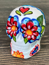 Load image into Gallery viewer, Inspired by nature, ceramic skull is full of vibrant colors and intricate details. The primary color is white with a black cat silhouette and multi-color floral motifs, along with hearts and leaves and lively colorful accents around the entire skull. Mini skull represented the eternal love for a special kitty cat in your life. Black cat silhouette is sitting on a tree branch admiring the starry night sky. Art created for all the cat lovers who adore their sweet kitty. Measurements: H 2 3/4” x W 2” x D 2”
