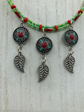 Load image into Gallery viewer, This adjustable necklace features an eye-catching Southwest-inspired design. Multi-hued glass beads, including bright green and vibrant red, are accompanied by dark red and green pendants with silver-plated feather charms. Ideal for chingona guerrera carbonas, la India princesses, warrior cosplay, and native-inspired looks. Measurements: Necklace is 15” adjustable up to 17" in length