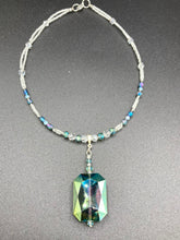 Load image into Gallery viewer, This gorgeous, Bohemian-style necklace features a shimmery aqua blue and gold-toned glass beaded design, with a large, faceted rectangular pendant adding dramatic flair. The vibrant and eye-catching colors make it the perfect way to add a pop of color to any ensemble and the draping style will give you a look that is both bold and elegant. Measurements: Necklace is 17” - adjustable to 18", pendant is 2 1/4”