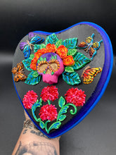 Load image into Gallery viewer, Frida Kahlo inspired calavera with a dark wood frame, this Day of the Dead wall decor piece is perfect for adding a traditional Mexican folk art touch to any home. Featuring an intricately detailed clay calavera in the style of Frida Kahlo, this Day of the Dead wall art decor is sure to be the centerpiece of any home décor. The calavera is wearing Frida's iconic crown of flowers and with several butterflies around her, ensuring it will bring both a unique and inspiring look to any wall.