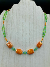 Load image into Gallery viewer, This unique, double-strand necklace consists of a blend of glass beads, including multi-green and rectangular, faceted orange glass beads, and is accented with gold and light blue elements. The vibrant combination is perfect for any summer look and will enhance any outfit.  Measurements:  Necklace is 16” and can be adjusted up to 18"