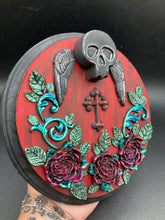 Load image into Gallery viewer, This Memento Mori Wall Art Decor is a one-of-a-kind art piece, skillfully crafted with a black polymer clay skull and wings on a dark red wood frame, decoratively woven with dark red roses and vines. It's perfect for adding an eye-catching touch to any wall and makes a unique, bold gift.  Measurements:  Diameter 6 3/4" x Depth 1 1/2"