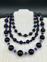 Load image into Gallery viewer, This Bohemian style necklace is composed of three strands of shimmery large black and dark purple glass beads, along with floral metal beads. The elegant drape creates a bold and fierce look that is ideal for a variety of occasions, such as cocktail chic attire and weddings. It is a perfect minimalist accessory.  Measurements:  Necklace is 16” in length - adjustable to 18"