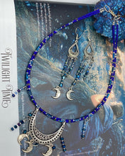 Load image into Gallery viewer, This stylish choker necklace showcases a large half moon pendant, adorned with glass beads and small, dangling crescent moon charms. Its eye-catching hues, of blue and silver, are complemented with delicate tints of purple and pink. Boasting an accentuated look and ample motion, this piece is sure to impress. Measurements: Necklace is 16 1/2”adjustable up to 18"