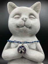 Load image into Gallery viewer, This stylish necklace features a shimmery sterling silver amethys pendant with cats and stars, making it the perfect accessory for any cat lover. With two-hole blue beads compliments the dark dark purple hues glass beads, this double strand necklace holds a round kitty pendant made with various hues of purple, blue and gold tone glass beads. Add a touch of purrfection to your look with this statement piece.   Measurements:  Necklace is 15 1/2” adjustable up to 18"