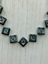 Load image into Gallery viewer, This two-strand necklace, crafted from aqua-blue and silver toned glass beads, is a stunning statement piece. The addition of faceted triangle-shaped glass beads tucked between hematite square beads adds an exquisite and unique flair. The necklace gracefully drapes around the neck, bringing an air of bold and elegant flair to any ensemble it complements. 15” in length, can be extended up to 17"