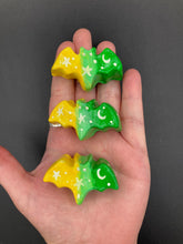 Load image into Gallery viewer, Cute and spooky magnet design to adorn your refrigerator, lockers, workstation, toolbox, or dishwasher. This hand-sculpted clay bat statuette boasts stunning ombre coloration, transitioning from to dark green to light green and then to bright yellow to recreate the breathtaking look of a starry night sky. H 1” x W 2” x D 1/2”