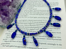 Load image into Gallery viewer, This Vibrant Royal Blue Glass Beaded Choker Necklace features two adjustable strands of deep blue beads with purple hues. The Bohemian style jewelry includes a mixture of rectangular-shaped blue, purple, and silver glass beads, which come together to create an eye-catching and elegant look. Perfect for any outfit, this draping necklace will add a vibrant and bold touch to your style. Measurements: Necklace is 14 3/4” in length, can be adjusted up to 16"