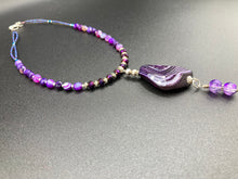 Load image into Gallery viewer, This double-stranded necklace is adorned with a large agate stone displaying a spectrum of purple shades, from light sheer to deep dark tones. The combination of purple agate and multi-colored glass beads makes this pendant a stunning addition to any summer look. Measurements: Necklace is 17” in length